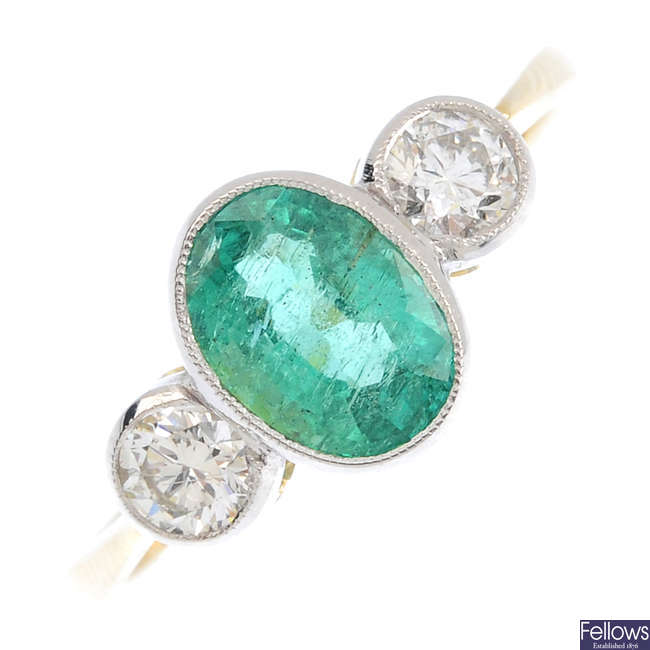 An emerald and diamond three-stone ring.