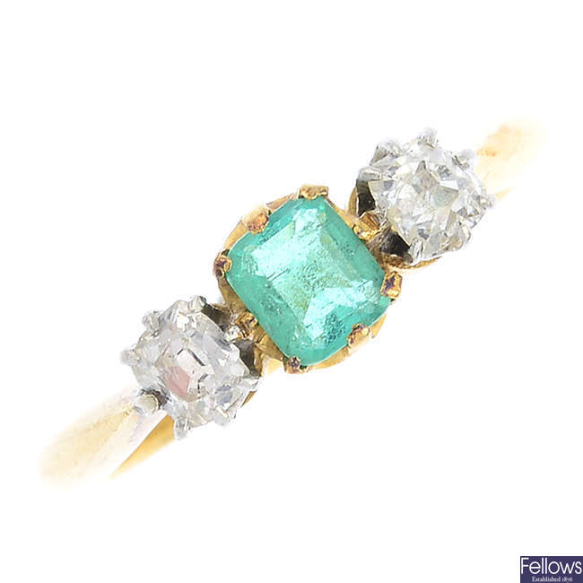 An emerald and diamond three-stone ring.