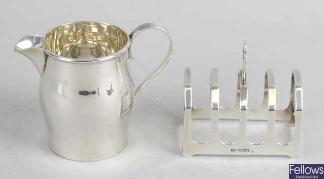An Edwardian silver cream jug & a 1930's small silver toast rack. (2).