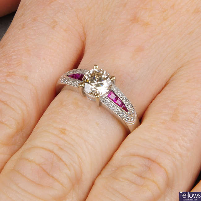 A brilliant-cut diamond single-stone ring, with calibre-cut ruby and pave-set diamond shoulders.