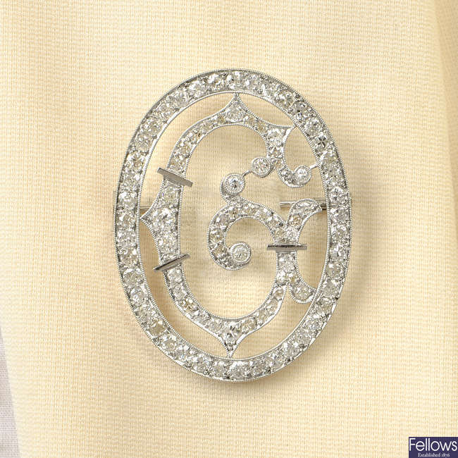 A mid 20th century platinum circular-cut diamond initial 'G' brooch.