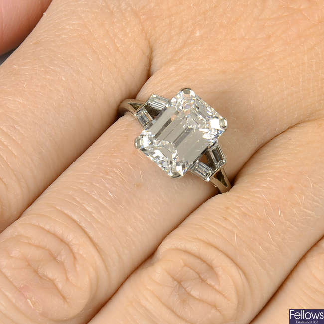 A cut-corner rectangular-shape diamond single-stone ring, with baguette-cut diamond chevron shoulders.