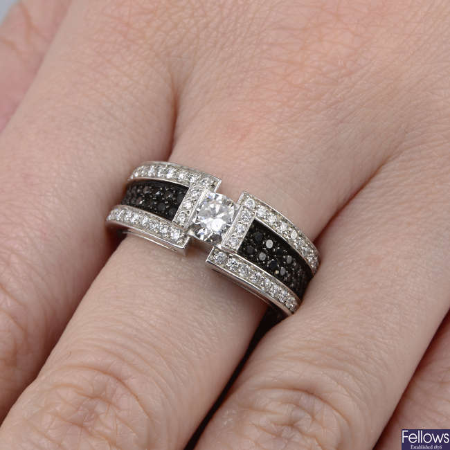 A brilliant-cut diamond single-stone ring, with pave-set diamond and black gem sides.