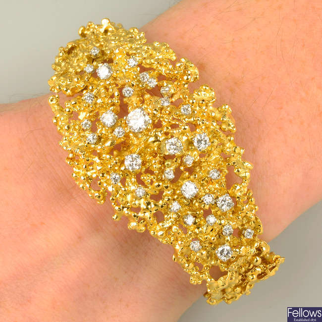 A 1970's textured openwork 18ct gold and scattered brilliant-cut diamond hinged bangle, by George Weil.