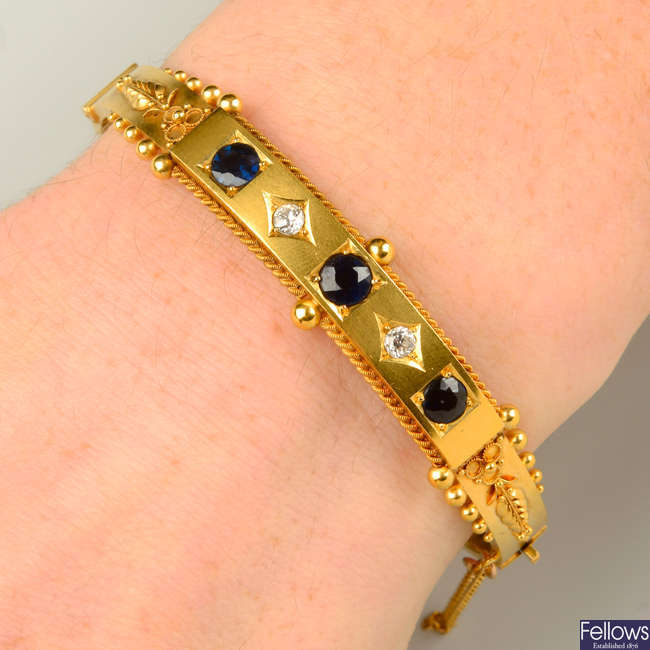 An early 20th century 15ct gold sapphire and circular-cut diamond hinged bangle, with foliate cannetille sides.