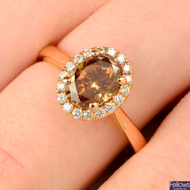 An oval-shape 'brown' diamond ring, with brilliant-cut diamond surround.