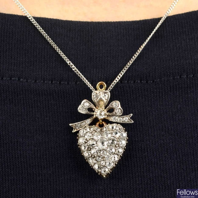 A late Victorian silver and gold old-cut diamond heart pendant, with similarly-cut diamond bow surmount.