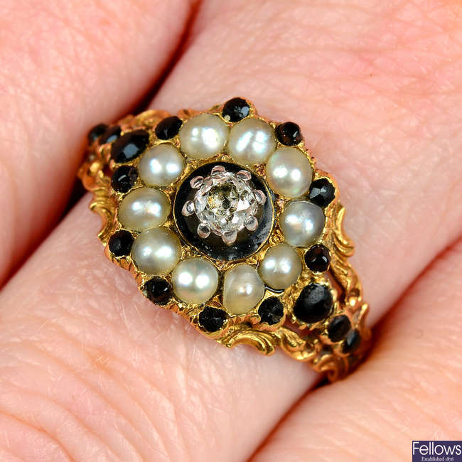 A Georgian 18ct gold black garnet, split pearl and old-cut diamond mourning ring, with floral shoulders.