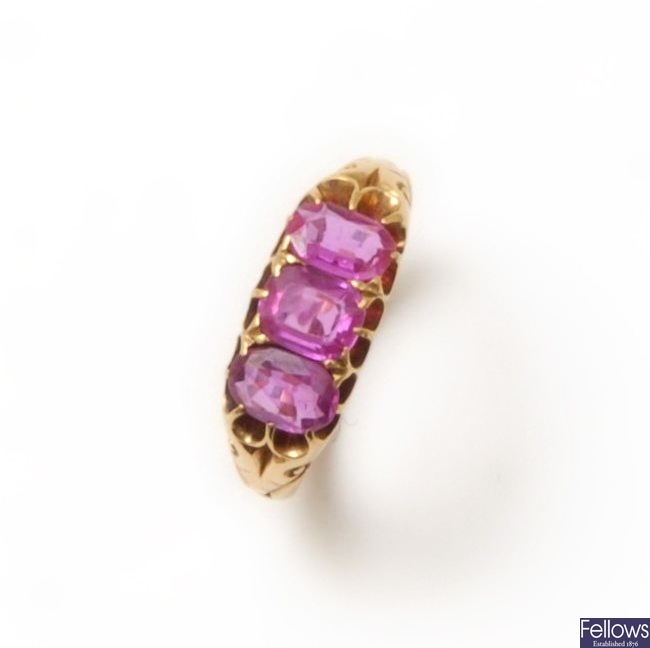 A three stone pink sapphire ring with scroll
