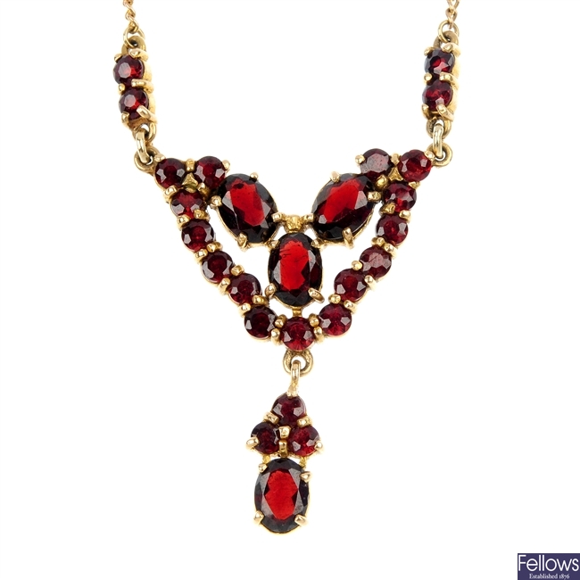 A 9ct gold garnet necklace and an emerald and diamond pendant.