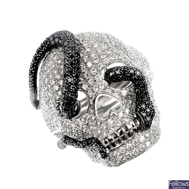 THEO FENNELL - an 18ct gold diamond and black diamond skull ring.