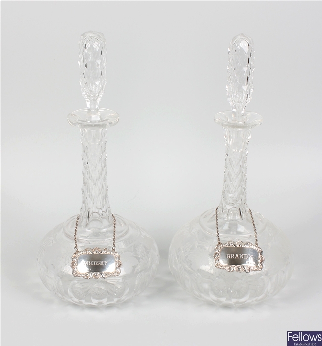 A pair of cut glass decanters with silver labels