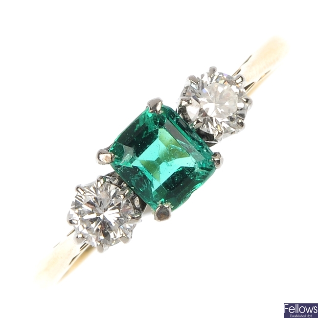 An emerald and diamond three-stone ring. 