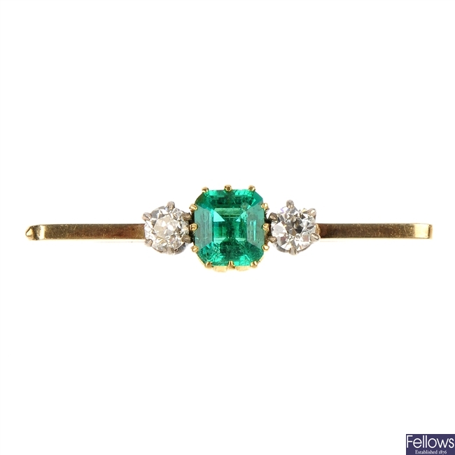 An emerald and diamond three-stone brooch.