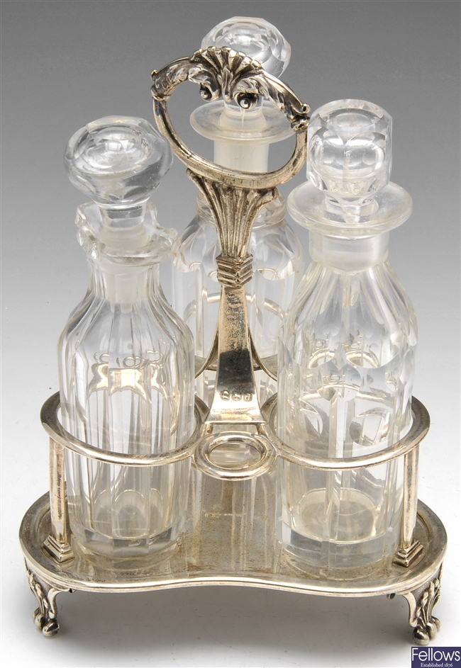 A George III cruet stand and three cut glass bottles.