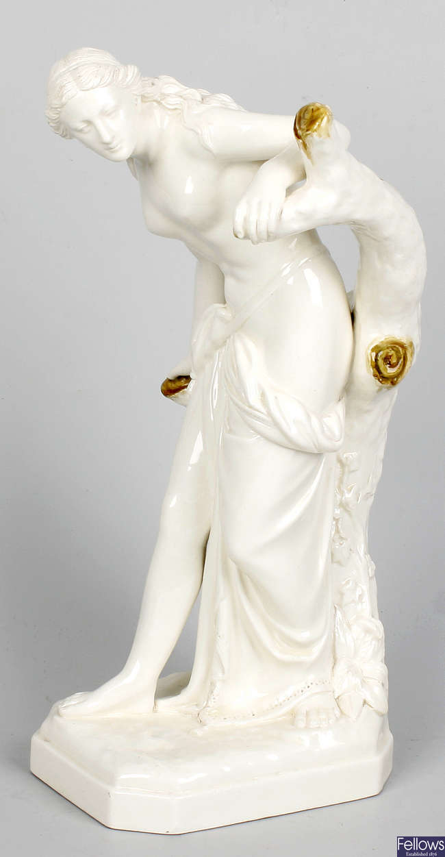 A Royal Worcester figure modelled as a semi naked female resting against the bough of a tree