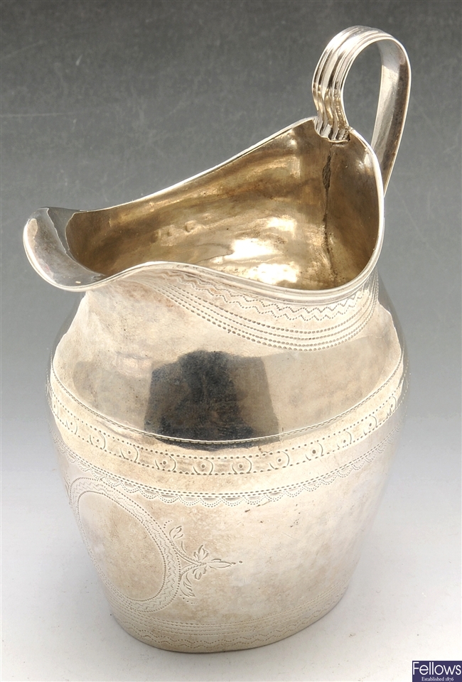 A George III silver cream jug with engraved decoration.