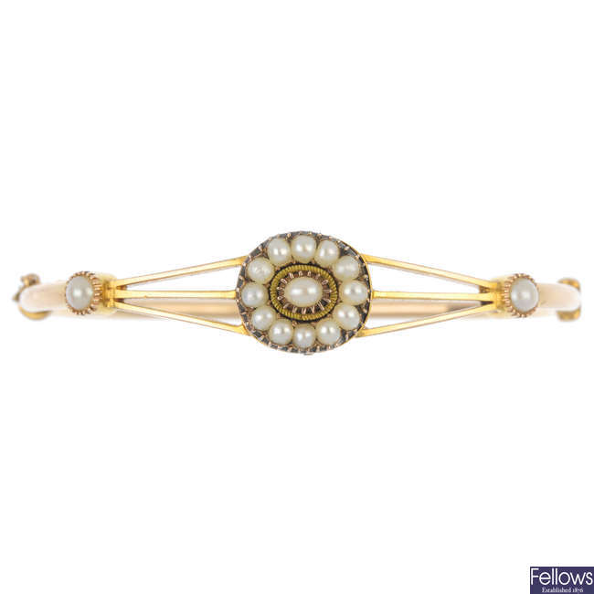 A late 19th century 15ct gold split pearl hinged bangle.
