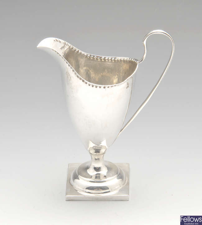 A George III silver cream jug of helmet form.
