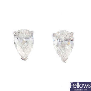 A pair of pear-shape diamond stud earrings.