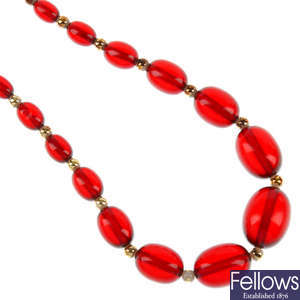 Two amber bracelets and a red plastic necklace.