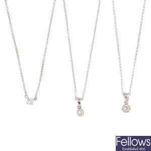 Three diamond single-stone pendants, with chains.