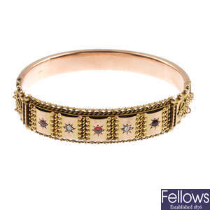 An early 20th century 9ct gold garnet and diamond hinged bangle.