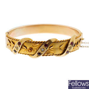 An early 20th century 9ct gold gem-set hinged bangle.