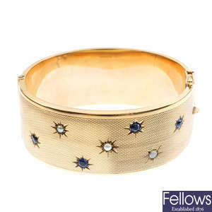 A 1950s 9ct gold sapphire and split pearl hinged bangle.