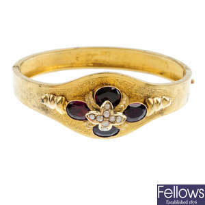 A late Victorian gold garnet and split pearl hinged bangle.