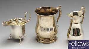 A 1920's silver mug, two silver cream jugs & a napkin ring. (4).