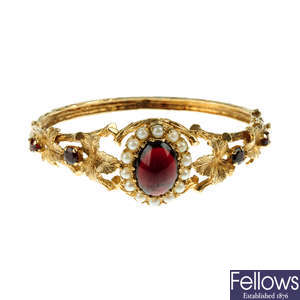 A 9ct gold bangle with red glass cabochon and split pearls.