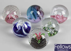 A collection of assorted coloured glass paperweights, to include a selection of Caithness and other named examples.