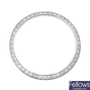 A white metal diamond set bezel in the style of Rolex.