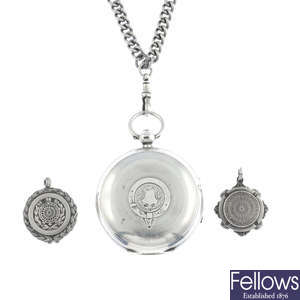 A silver pocket watch with three fobs.