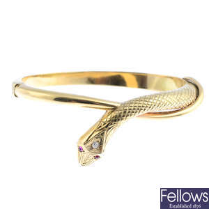 A 9ct gold diamond and ruby snake hinged bangle.