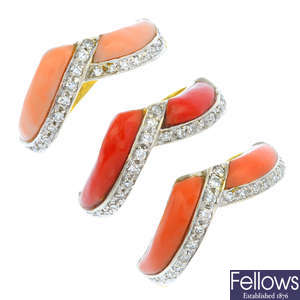 A set of three coral and diamond rings.