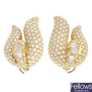A pair of pave-set and tapered baguette-cut diamond scroll earrings.