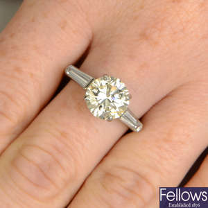 A brilliant-cut diamond diamond single-stone ring, with tapered baguette-cut diamond sides.
