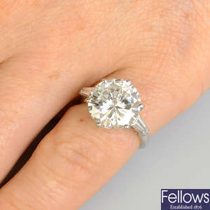 A brilliant-cut diamond single-stone ring, with tapered baguette-cut diamond shoulders.