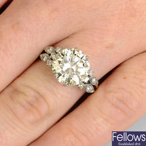 A brilliant-cut diamond single-stone ring, with diamond shoulders.