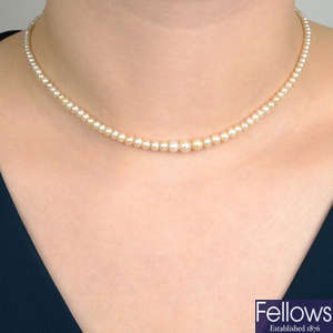 An early 20th century natural pearl single-strand necklace, with old-cut diamond cluster clasp.