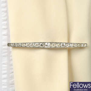 An early 20th century platinum and gold graduated old-cut diamond bar brooch.