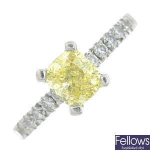 A platinum cushion-shape Fancy Intense Yellow diamond single-stone ring, with brilliant-cut diamond line sides.