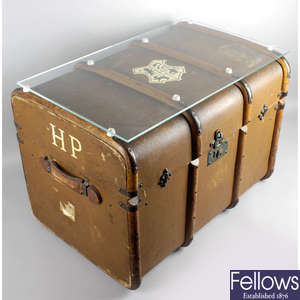 An old brown canvas and wooden bound travel trunk, with applied Hogwarts crest to top and H.P initial to end.