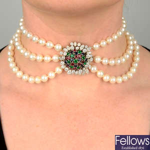A mid 20th century cultured pearl three-strand choker necklace, with ruby, sapphire, emerald and vari-cut diamond cluster clasp.