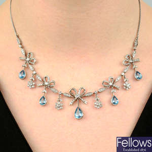 An 18ct gold brilliant-cut diamond bow necklace with aquamarine and floral fringe.