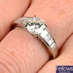 A platinum brilliant-cut diamond single-stone ring, with graduated baguette-cut diamond shoulders.