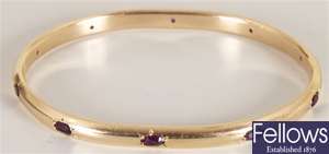An amethyst set bangle, set with ten oval spaced