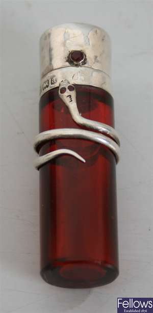A cylindrical cranberry glass scent bottle with